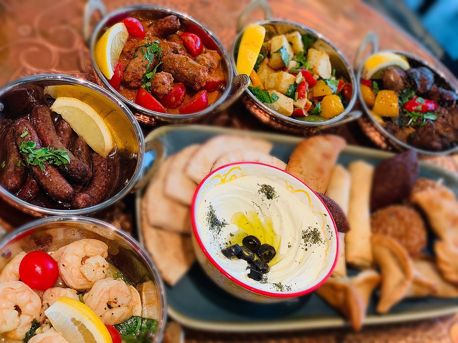 Copper bowls of mezze with labneh, prawns, kebbeh and pastries